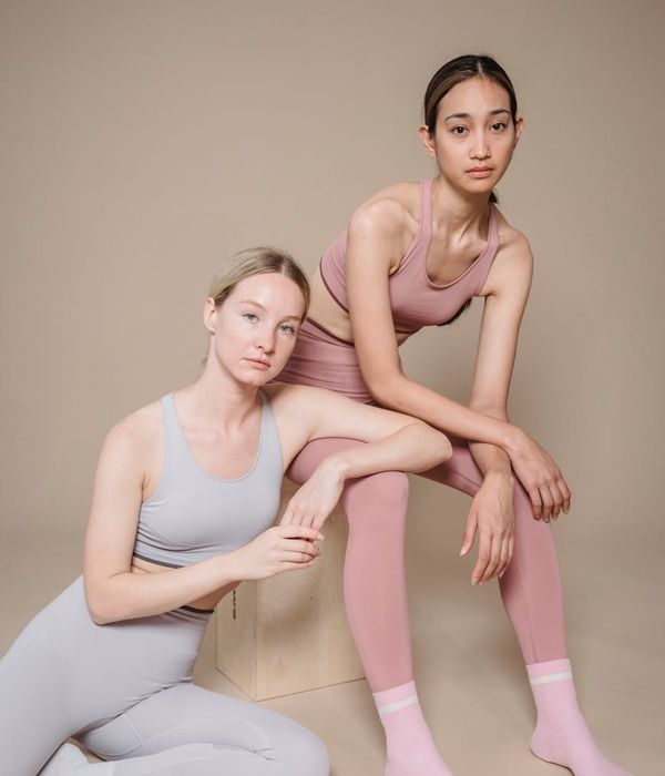 Woman in a calm yoga pose in a studio with soft iris-colored light.